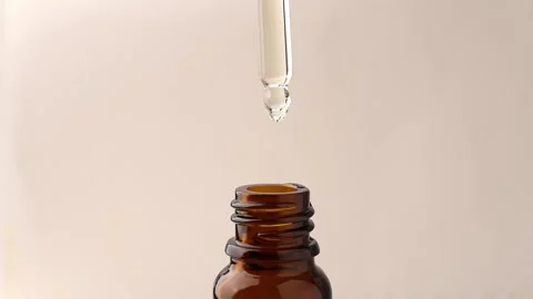 Pipette with drops of oil falling into a brown bottle, close-up. Stock Footage 170476512