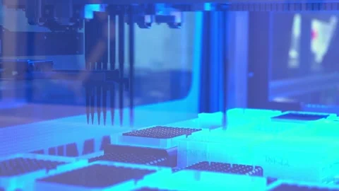 The pipette head of a DNA sequencing machine lowers over sample trays under Stock Footage 345299337