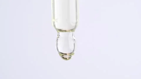 Pipette with serum, close up. Drops of essential oil fall from a glass pipe.. Stock Footage 269330850