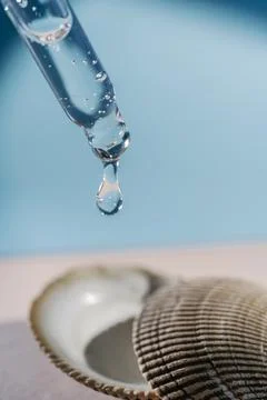 Pipette with transparent serum on the background of shells. Stock Photos