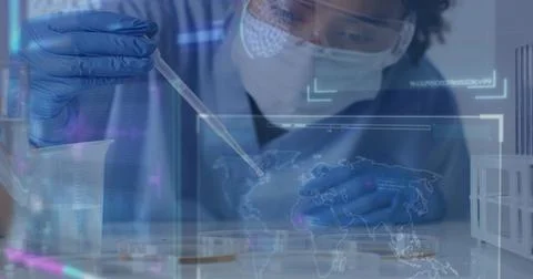 Pipetting tech with PPE at lab bench using pipette placing droplet into Stock Photos