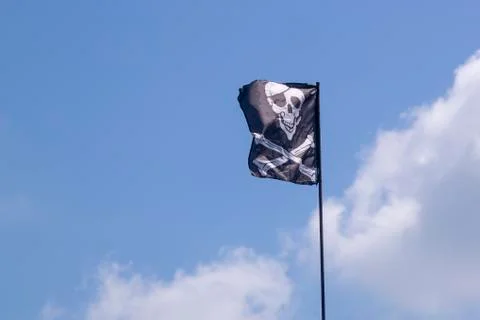 Pirate flag develops in the wind, skull with bones, Jolly Roger Stock Photos
