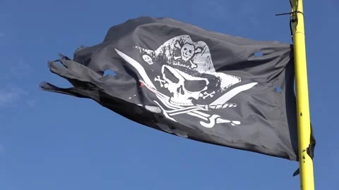 A pirate flag on a flagpole blows in the wind slow motion Stock Footage 267439509