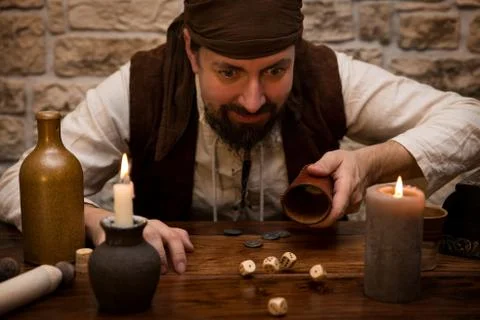 Pirate is gambling with dice on a medieval table, concept luck and success 스톡 사진