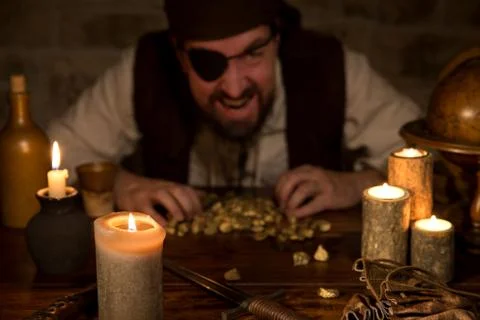 Pirate with a treasure of gold behind a lot of candles Stock Photos