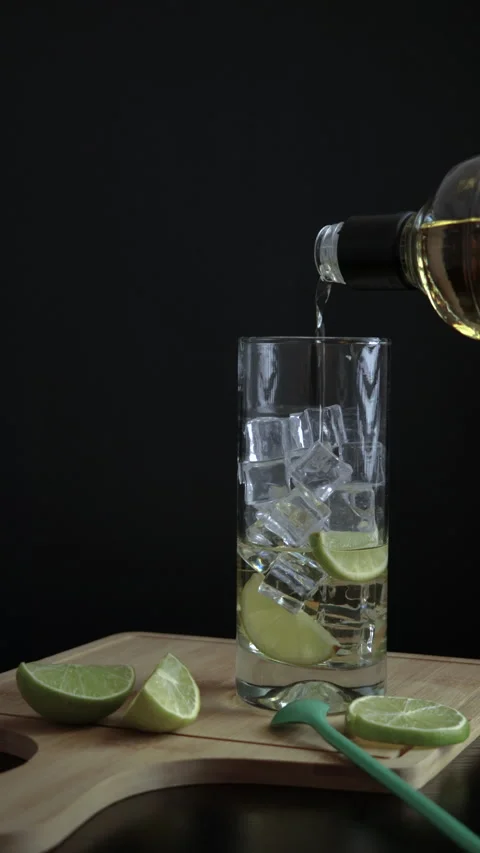 Piscola, preparing, cocktail, adding, pisco, glass with ice, wooden board, cu Stock Footage 262494610