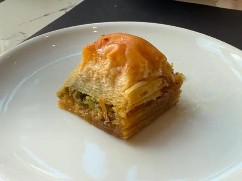 Pistachio baklava portion served on a white plate with crisp layered phyllo a Stock Photos