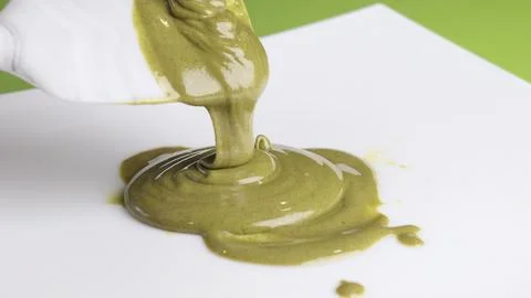 Pistachio cream, paste drip on spatula on white background. Food and creams Stock Photos