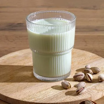 Pistachio milk in glass with nuts on table, vegan plant based drink, dairy .. Stock Photos