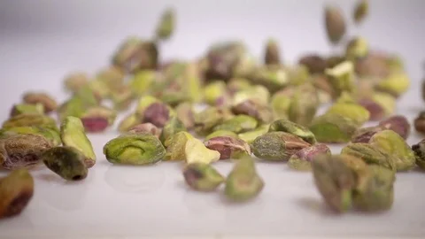 Pistachio nuts falling onto white background, slow motion Stock Footage 76386138