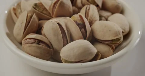 Pistachio nuts rotating in a bowl isolated on white background Stock Footage 344321493