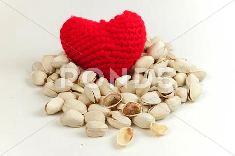 Pistachios and Knitting yarn to form a red heart. Stock Photos