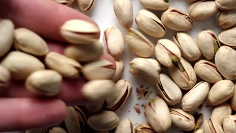 Pistachios falling from hand on ceramic plate. Stock Footage 335686856