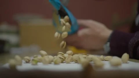Pistachios falling in slow motion from a bag on a kitchen's table Stock Footage 263959693