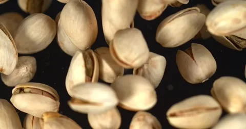 Pistachios falling in slow motion on black background top view Stock Footage 347446628