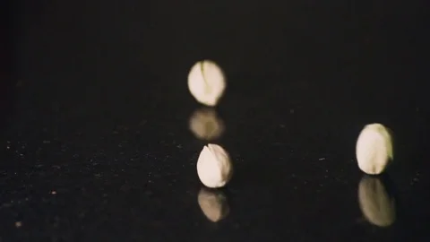Pistachios falling in slow motion on to a dark counter top Video stock 71936376