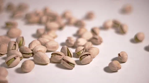 Pistachios falling in slow motion on white table - Track Shot Video stock 61396917