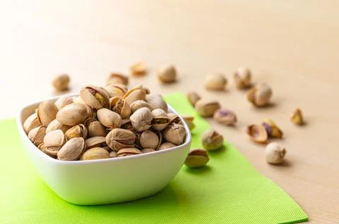 Pistachios in shell in white bowl. Stock Photos