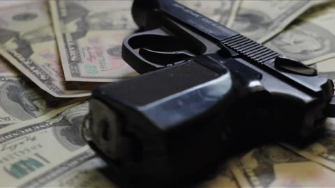 Pistol and stack of dollar cash papers rotating Stock Footage 233469234