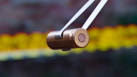 Pistol bullet shell held by tweezers. Examine evidence of a crime. Ammunition Vidéo 201216583