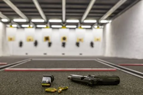 Pistol on an empty indoor shooting range Stock Photos