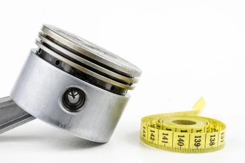 A piston from an internal combustion engine and a tailor measure on a white t Stock Photos