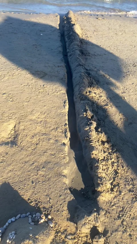 A pit on the beach. Sand structures on the beach. Vertical video Stock Footage 287499005