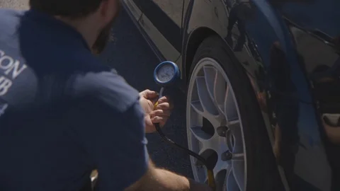 Pit crew measuring tire pressure of race car   Stock Footage 127641941