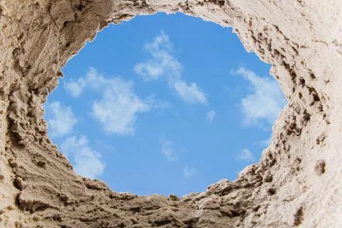 Pit in the sand on the beach. View from the pit. blue sky. Stock Photos