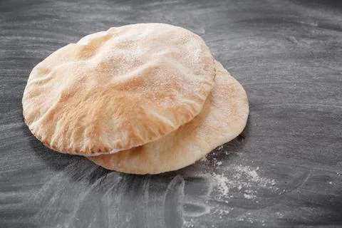 Pita bread on a black table sprinkled with flour Stock-Fotos