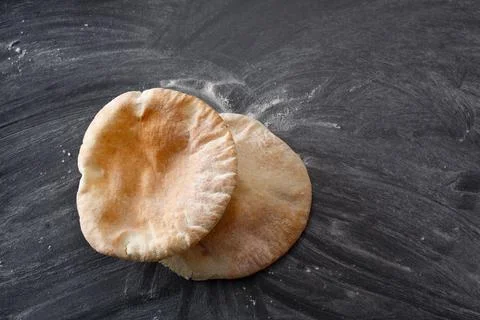 Pita bread on a black table sprinkled with flour Stock Photos