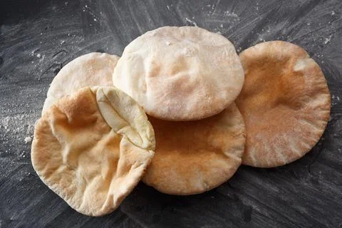 Pita bread on a black table sprinkled with flour Stock Photos