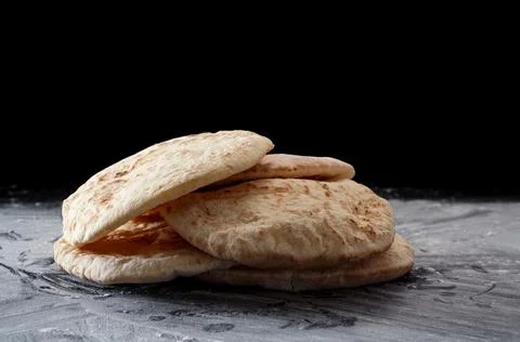 Pita bread on a black table sprinkled with flour Stock Photos