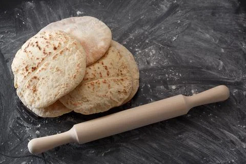 Pita bread on a black table sprinkled with flour Stock Photos