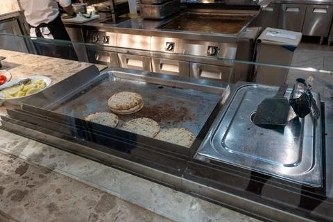 Pita bread heating on professional flat top grill at buffet Foto stock