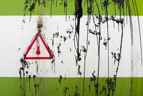 Pitch splashes on container and warning sign of hot dangerous material Stock Photos