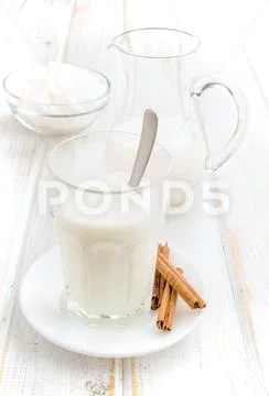 Pitcher and glass of milk with sugar cubes on wood Stock Photos