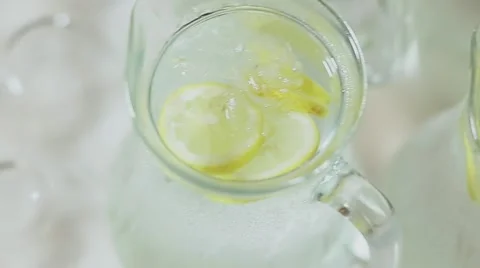Pitcher of cold water with ice cubes and fresh lemon slices Stock Footage 56869707