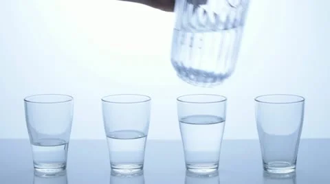 Pitcher is filling up four glasses with different levels. Stock Footage 11606383