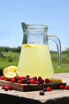 Pitcher of ice cold lemonade and fruit outside in summer Stock Photos