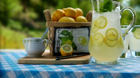 Pitcher of lemonade and glasses getting pickup on a table outside Stock Footage 33994109
