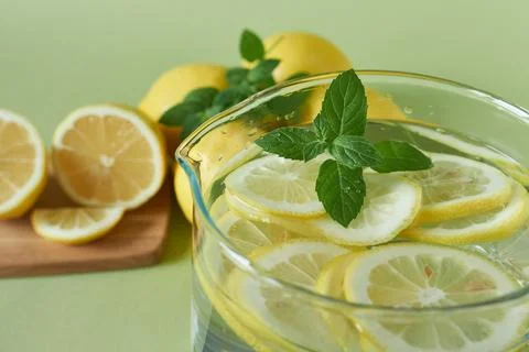 A pitcher of lemonade with mint and lemons on a green background, closeup Stock Photos