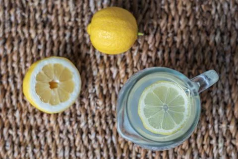 Pitcher of lemonade with a slice of lemon on top, accompanied by half a lemon Stock Photos