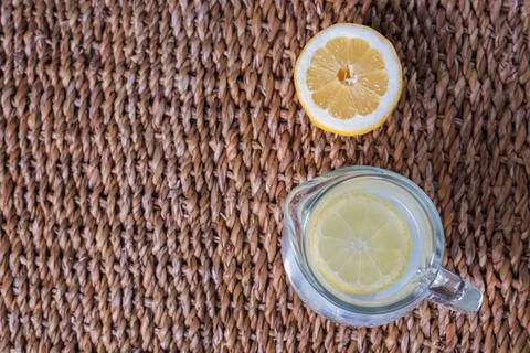 Pitcher of lemonade with a slice of lemon on top, accompanied by half a lemon Stock Photos