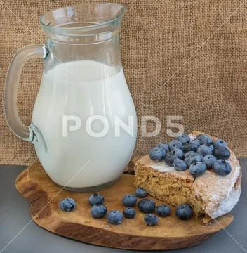 Pitcher with milk,cake and blueberry in the plate Stock Photos