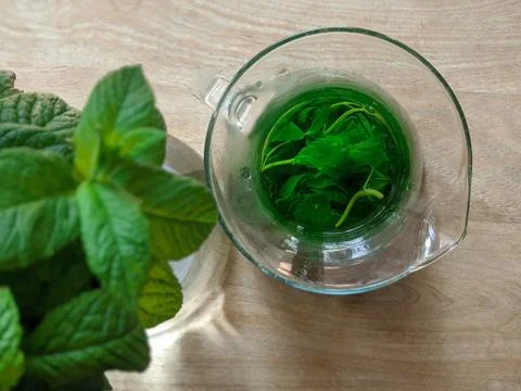 Pitcher with mint tea and a bunch of mint leaves on wooden table Stock Photos