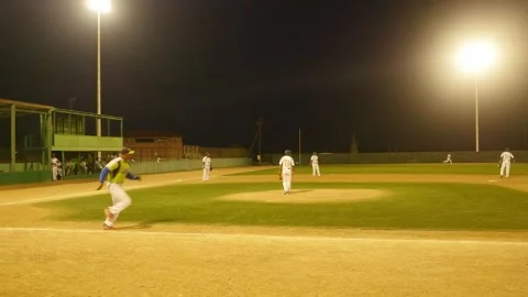 Pitcher pitches the ball and batter hits and runs to first base in Softball Stock Footage 255377041