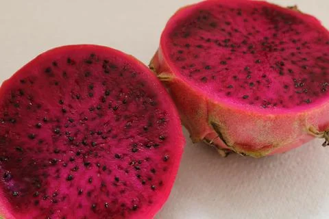 Pithaya cut in half showing dark pink interior and black seeds Stock Photos
