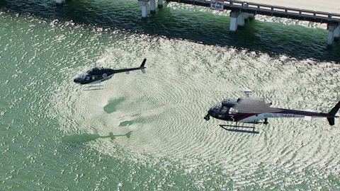 Pivoting abover two helicopters hovering over water Stock Footage 136201201
