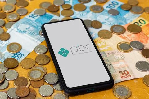 Pix logo on smartphone screen with multiple coins around Stock Photos